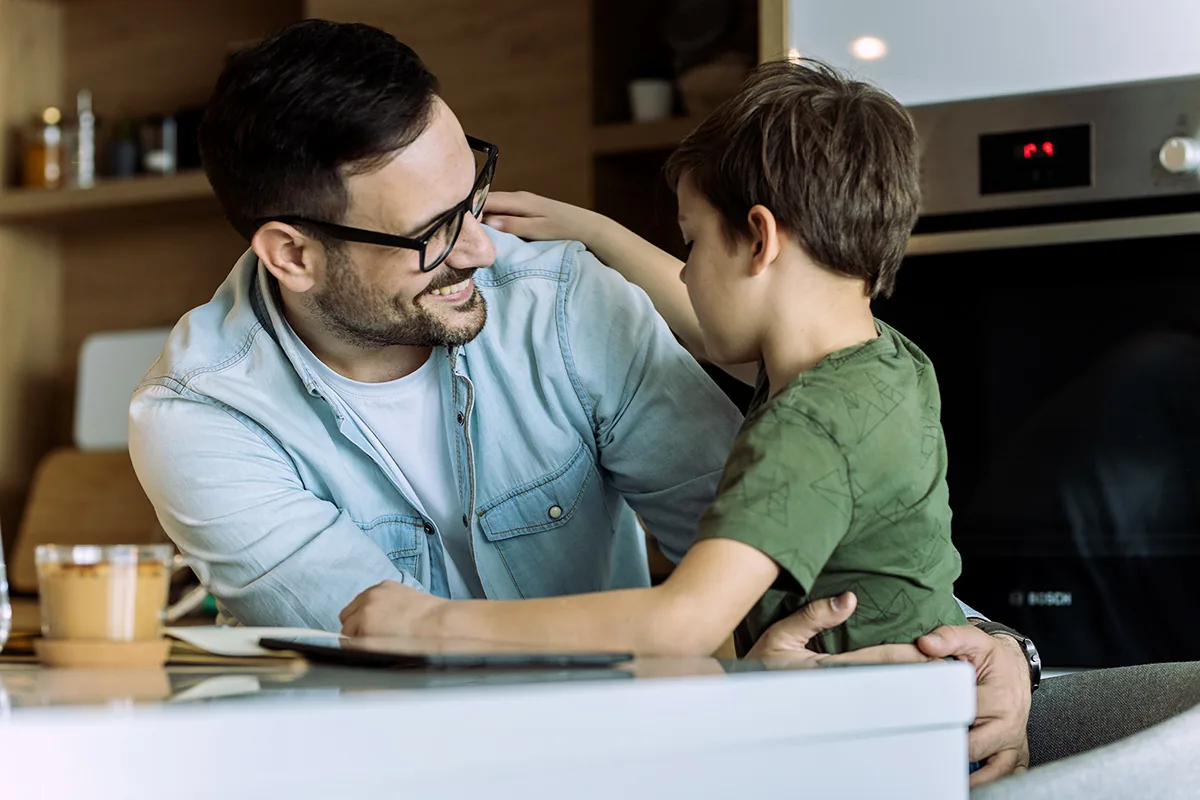 A father talks with his young son at the kitchen table